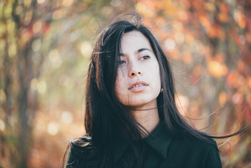 Female beauty portrait surrounded by vivid foliage. Dreamy beautiful girl with long natural black...
