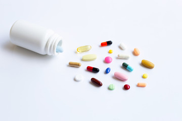 Colorful tablets with capsules and pills on white.
