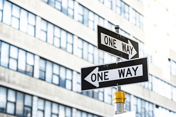 Close-up view of 'one way' road sign with blurred building in the background. Manhattan, New York...