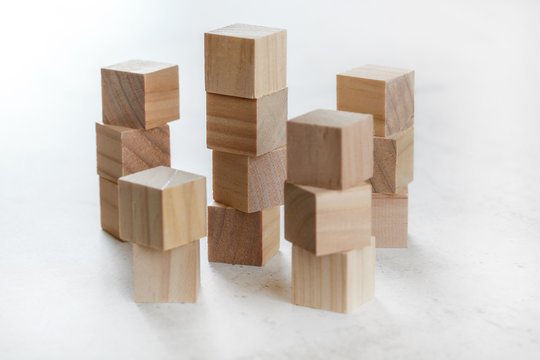 Stacks of wooden toy cubes creating small towers on white board
