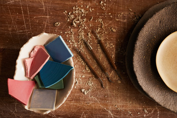 High angle view of handmade ceramics pieces in bowl, stack of textured plated and various craft...