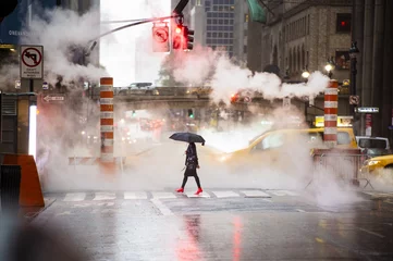 Foto op Plexiglas Een vrouw met een paraplu en rode schoenen met hoge hakken steekt de 42nd street in Manhattan over. Auto& 39 s en stoom die uit de mangaten op de achtergrond komen. New York City, VS. © Travel Wild