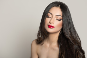 Woman with red lipstick and dark thick hair. Eyes closed