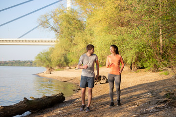 Young  man and woman jogging outdoors near river