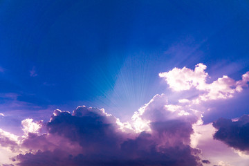 Beautiful blue sky with sunrays rising from behind clouds