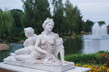 Ancient women statue in lakel and park background.