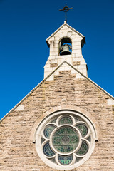 Bell tower of a Catholic Chapel, against a blue sky.