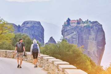 Hiking young couple tramping on asphalt road in sunset from back. Travel vacation, hiking...