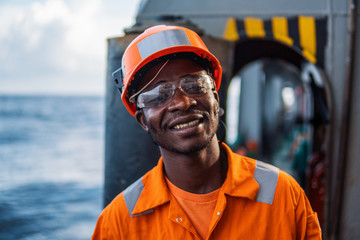 happy Seaman AB or Bosun on deck of vessel or ship , wearing PPE personal protective equipment -...