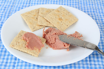 Seriously unhealthy snack of processed potted meat on saltine crackers.