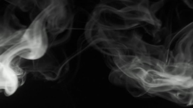 Vertical video screensaver -  Trickle of gray smoke slowly rising graceful twists upward. Black and white cigar smoke blowing from the left side. Closeup, isolated on black background.