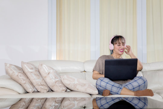 Happy woman listening music by uses a laptop