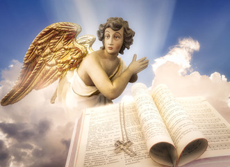 Praying angel with golden wings in heaven with a catholic Hymn Book