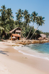 White sand & blue water in Tangalle. Goyambokka beach with palm & house on the shore, in the southern province of Sri Lanka. Majestic bay in Indian Ocean. Waves breaking on the most beautiful stones.