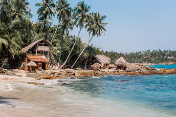 White sand & blue water in Tangalle. Goyambokka beach with palm & house on the shore, in the southern province of Sri Lanka. Majestic bay in Indian Ocean. Waves breaking on the most beautiful stones.
