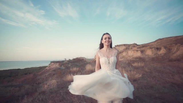 Running bride in amazing long dress through the landscape. Happy moments