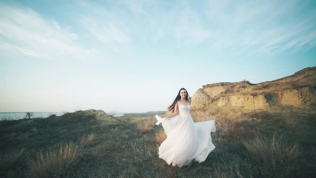 Running bride in amazing long dress through the landscape. Happy moments