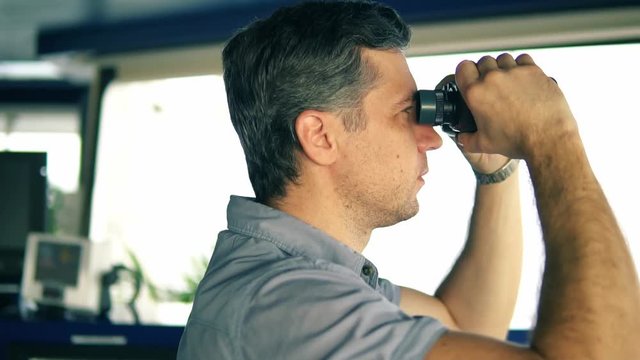 Navigational officer lookout on navigation watch looking through binoculars. Marine industry. COLREG collision regulations