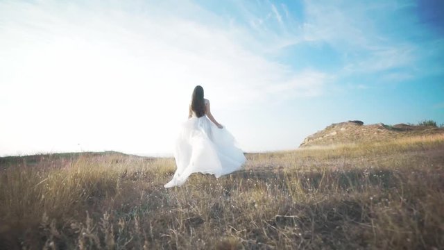 Running bride in amazing long dress through the landscape. Happy moments