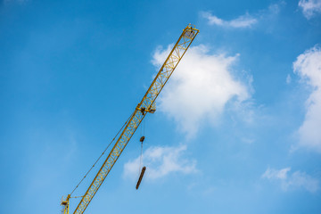 Tower crane at the construction site of blue sky and white clouds.