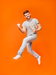 Fototapeta na wymiar Lucky man celebrating and jumping on orange background