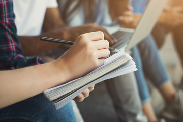 Teen girl writing notes in notebook outdoor