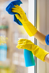Gloved hand cleaning window rag and spray