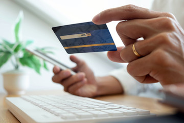 Using a credit card to pay online, use a smartphone for online shopping, a male hand holds a credit card.