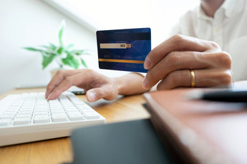 Fototapeta premium Using a credit card to pay online, use a smartphone for online shopping, a male hand holds a credit card.