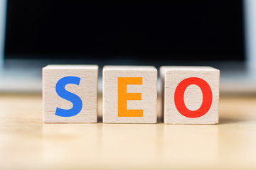 Search engine optimization concept. Wooden block cube shape with word SEO and laptop
