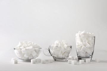 Glass, coffee mug, glass bowl filled with sugar cubes Concept of food that is not healthy