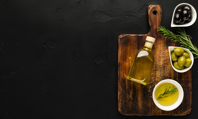 Olive oil and olives in bowls on board.
