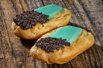 Delicious eclairs on wooden board