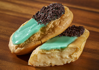 Delicious eclairs on wooden board