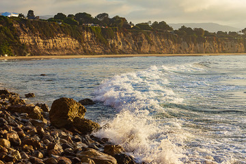 splashes from wave hitting rock in sunny california day with light