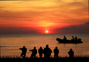Fototapeta na wymiar Navy seal silhouettes on sunrise 