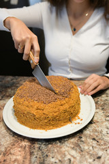 Mom cuts and serves a piece of freshly baked cake, which they have just made at home. The girl baked a cake and slices it.