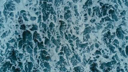 aerial drone image top looking down of surf waves rolling over a reef with white water break