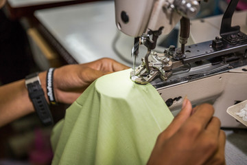 seamstress on a sewing machine makes a shirt in the sewing workshop. close-up partial view of seamstress working.