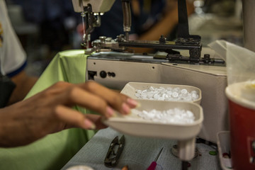 seamstress on a sewing machine makes a shirt in the sewing workshop. close-up partial view of seamstress working.