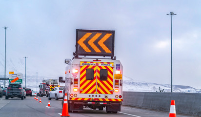 Back view of an emergency vehicle with an arrow board mounted on the roof