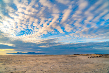 Boundless blue sky with gray and white clouds over a vast sandy shore - Powered by Adobe
