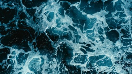 aerial drone image top looking down of surf waves rolling over a reef with white water break