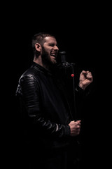 rock musician singing on a microphone. Shot on a black background.