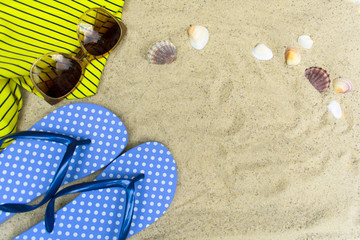 Blue  flip flops, sunglasses on sandy beach with seashells