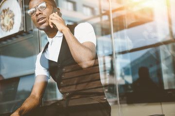 Young african american business man in suit and eyeglasses talking on the phone on the background of the business center