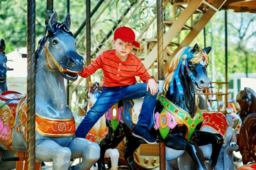 Fototapeta na wymiar Beautiful boy posing on the carousel . The concept of children's summer holiday