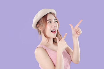 Korean woman point to special deals & discounts of promotions, tank top with beret hat, purple background