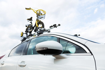 Bicycle transport - a children's bicycle on the roof of a car against the sky in a special mount for cycling. The decision to transport large loads and travel by car