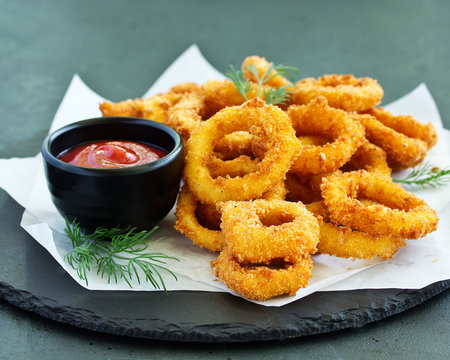 Homemade crunchy fried onion rings with tomato sauce